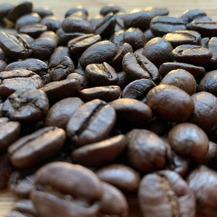 A close-up view of dark-roasted coffee beans, displaying their deep, rich color and oils.