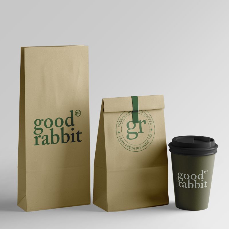 Two craft coffee pouches and a disposable cardboard cup with a plastic lid, ready to serve freshly brewed dark-roasted coffee.